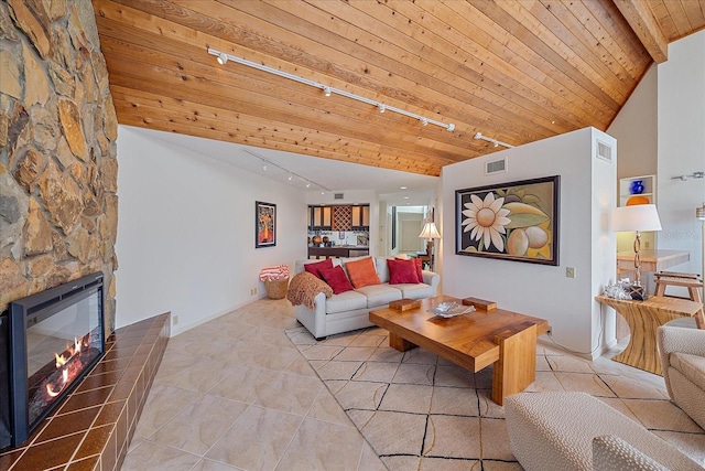 tiled living room with rail lighting, a stone fireplace, and wooden ceiling