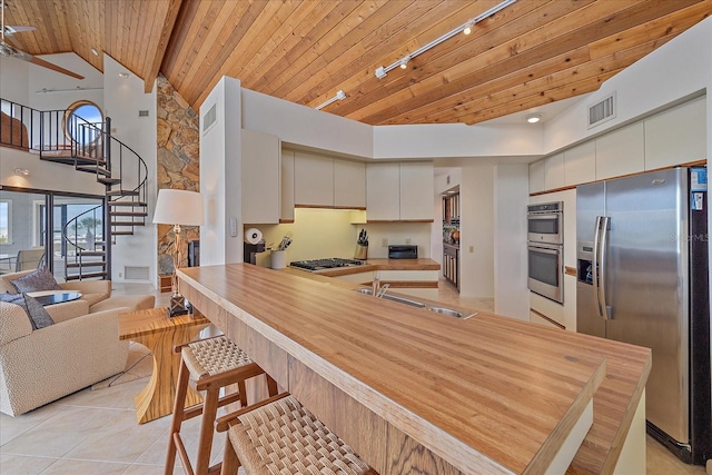 kitchen featuring stainless steel appliances, wood ceiling, a peninsula, a sink, and light tile patterned floors