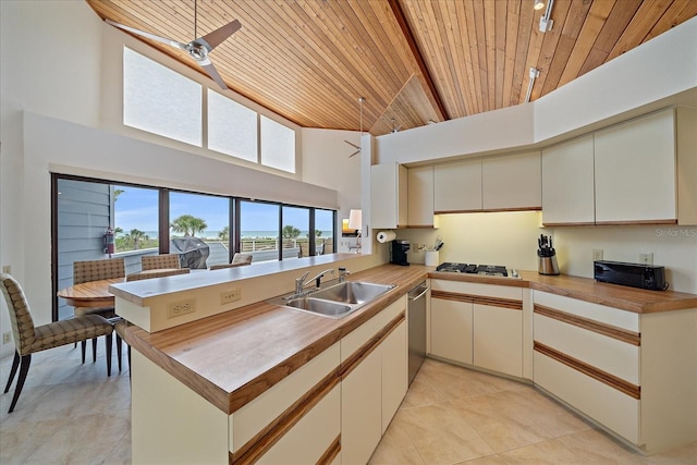 kitchen with a high ceiling, wooden ceiling, light tile patterned floors, a sink, and a peninsula