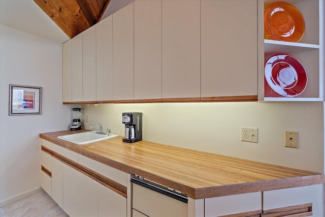 kitchen featuring a sink, wood ceiling, white cabinets, lofted ceiling, and baseboards
