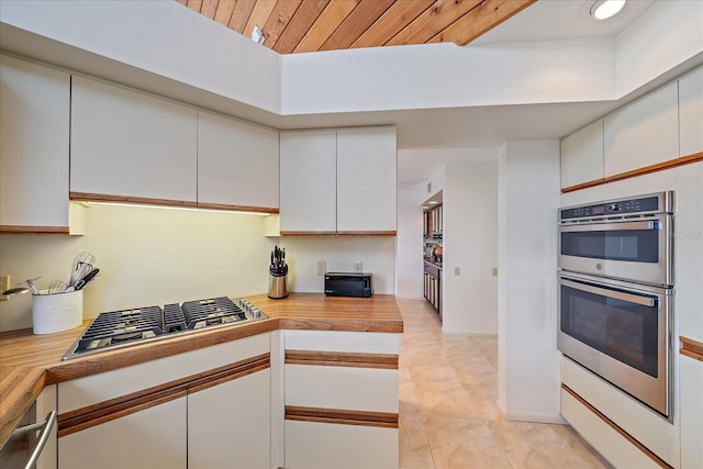 kitchen featuring appliances with stainless steel finishes, white cabinets, wood ceiling, and light tile patterned floors