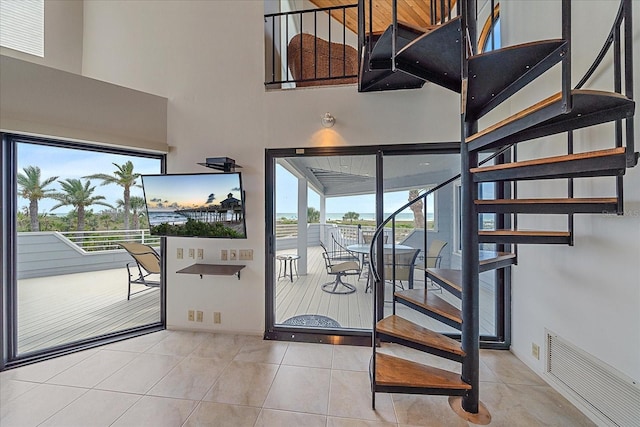stairs featuring a high ceiling, baseboards, and tile patterned flooring