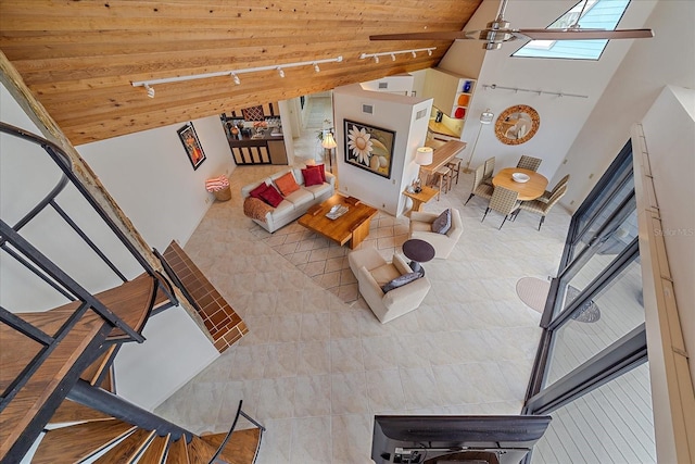 living area featuring ceiling fan, high vaulted ceiling, wooden ceiling, a skylight, and track lighting
