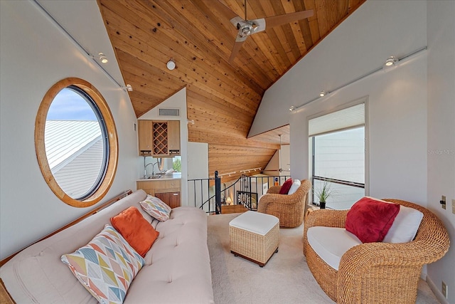 carpeted living area featuring lofted ceiling, wood ceiling, wood walls, a ceiling fan, and a sink