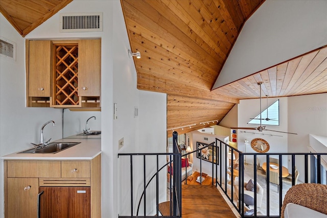 hallway featuring lofted ceiling, wood ceiling, a sink, wood finished floors, and an upstairs landing