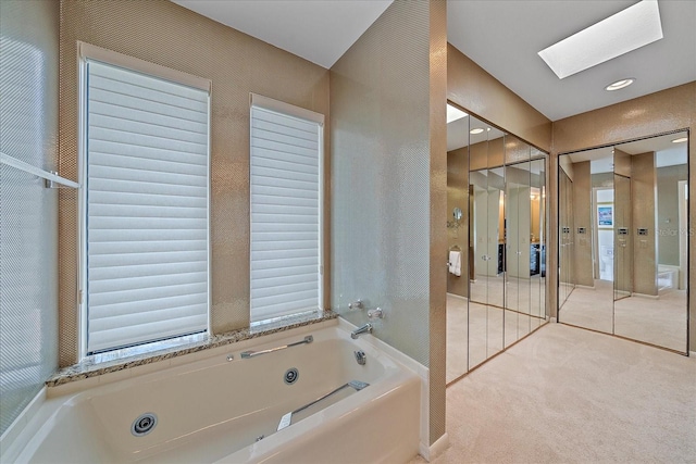 bathroom featuring a whirlpool tub and a skylight