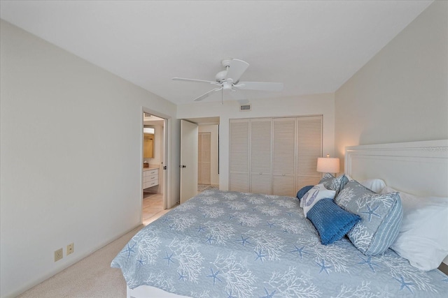 bedroom featuring a closet, light colored carpet, a ceiling fan, and ensuite bathroom
