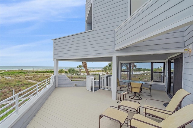 wooden deck with view of water and beach