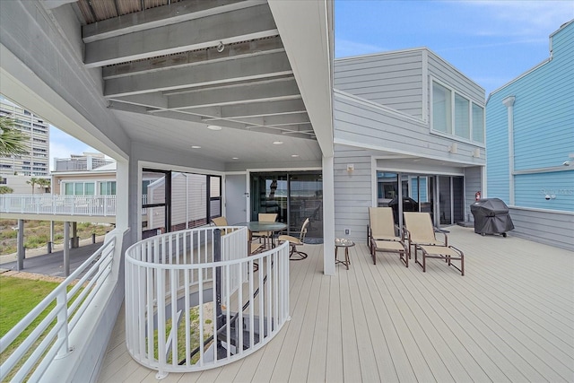 wooden terrace featuring a grill and outdoor dining space