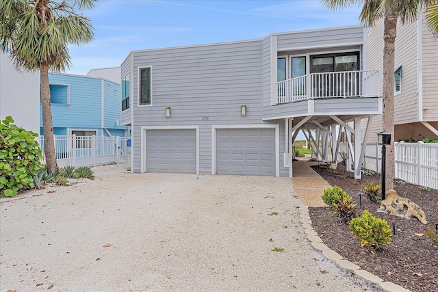 coastal inspired home featuring a garage, dirt driveway, and fence