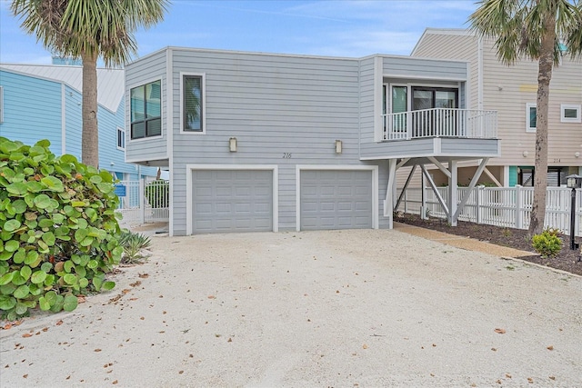 view of front facade with a garage, driveway, and fence