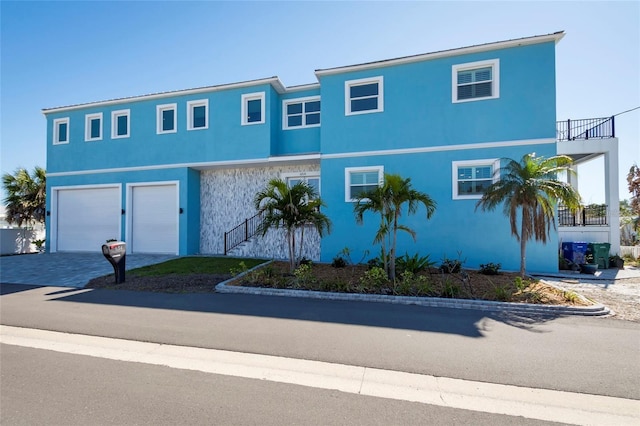 view of property with an attached garage, driveway, and stucco siding