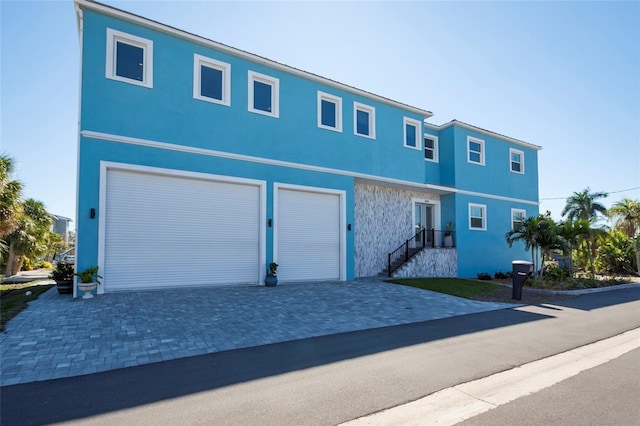 view of front of home featuring driveway, stone siding, and stucco siding