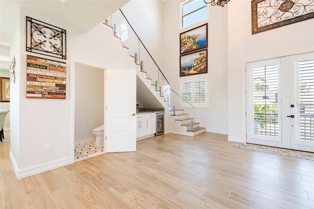 entryway featuring a healthy amount of sunlight, stairs, beverage cooler, and a towering ceiling