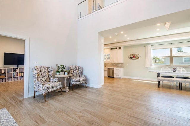 living area with recessed lighting, baseboards, a high ceiling, and light wood-style floors