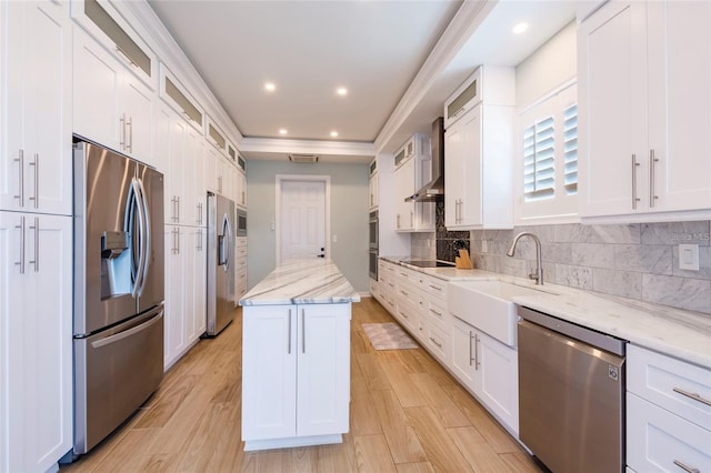 kitchen with white cabinets, stainless steel appliances, a sink, and wall chimney exhaust hood