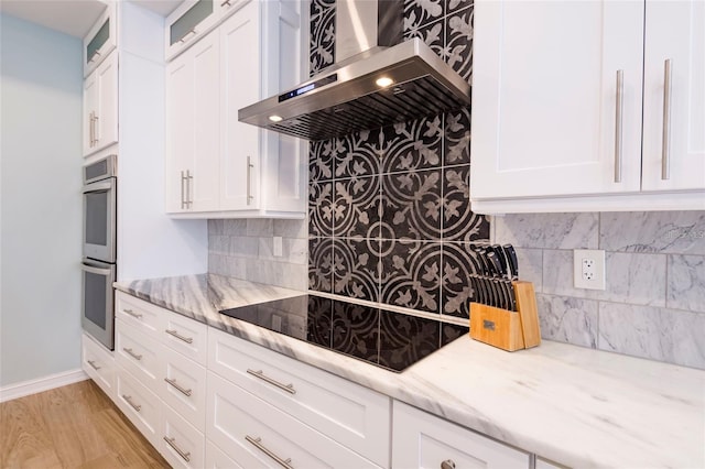 kitchen featuring decorative backsplash, stainless steel double oven, light stone counters, ventilation hood, and black electric stovetop