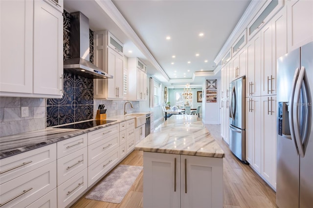 kitchen featuring a center island, light stone countertops, white cabinetry, stainless steel appliances, and wall chimney exhaust hood