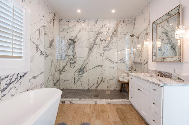 bathroom featuring vanity, a freestanding tub, tile walls, recessed lighting, and a marble finish shower