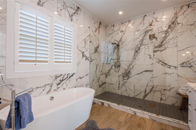 bathroom with tile walls, wood finished floors, a marble finish shower, a soaking tub, and recessed lighting