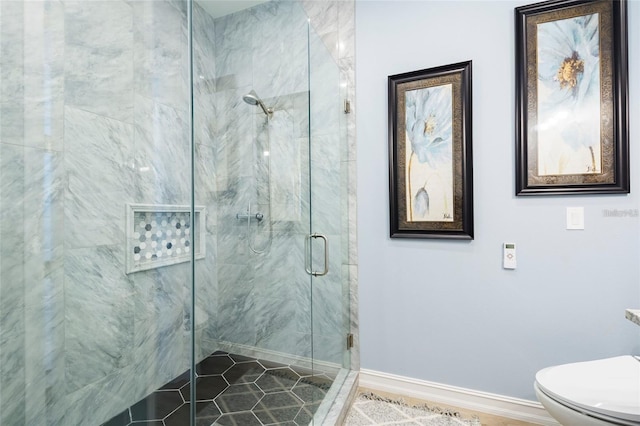 bathroom featuring baseboards, a marble finish shower, and toilet