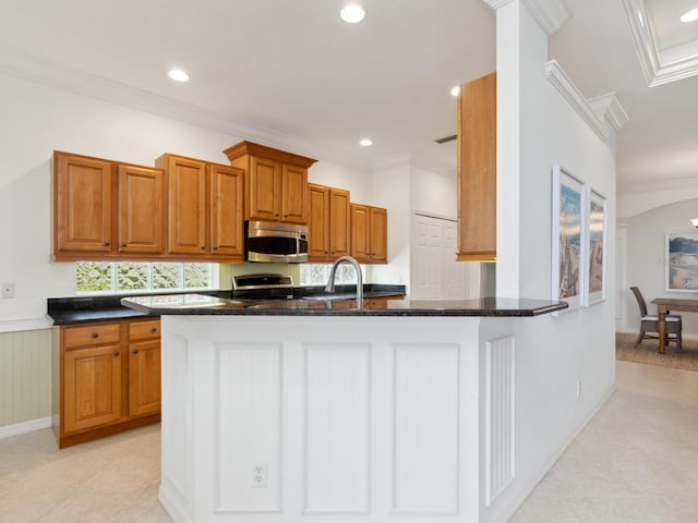 1313 Thornapple Dr, Osprey, FL 34229 - kitchen featuring stainless steel microwave, crown molding, brown cabinetry, range, and dark stone counters