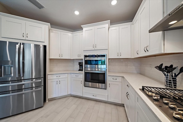 kitchen featuring visible vents, decorative backsplash, under cabinet range hood, white cabinets, and stainless steel appliances