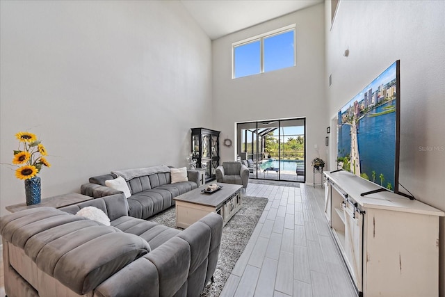 living area featuring high vaulted ceiling, light wood-style flooring, and a wealth of natural light