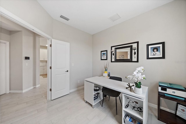 home office featuring baseboards, visible vents, and light wood finished floors
