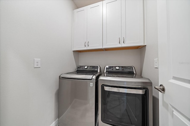 clothes washing area with baseboards, washer and clothes dryer, and cabinet space
