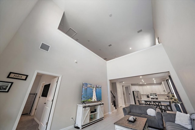 living room featuring visible vents, baseboards, and a towering ceiling