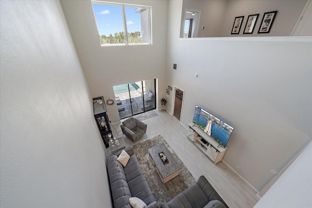 living area with baseboards, visible vents, wood finished floors, and a towering ceiling