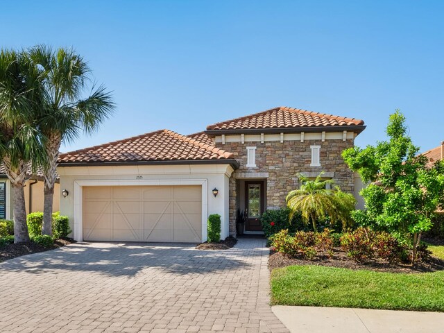 2525 Vaccaro Dr, Sarasota, FL 34231 - mediterranean / spanish-style house with an attached garage, stucco siding, a tiled roof, and stone siding