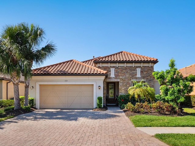 2525 Vaccaro Dr, Sarasota, FL 34231 - mediterranean / spanish home with stone siding, a garage, stucco siding, a tiled roof, and driveway