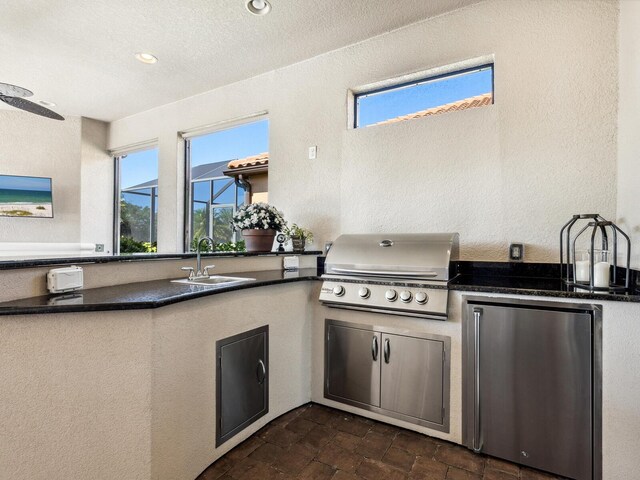 2525 Vaccaro Dr, Sarasota, FL 34231 - kitchen with stone finish flooring, dark countertops, refrigerator, a sink, and a textured wall