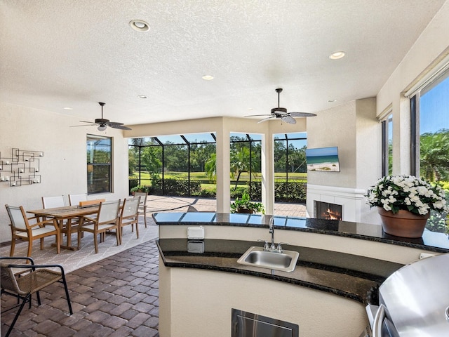 2525 Vaccaro Dr, Sarasota, FL 34231 - kitchen featuring a ceiling fan, a lit fireplace, a sink, and recessed lighting