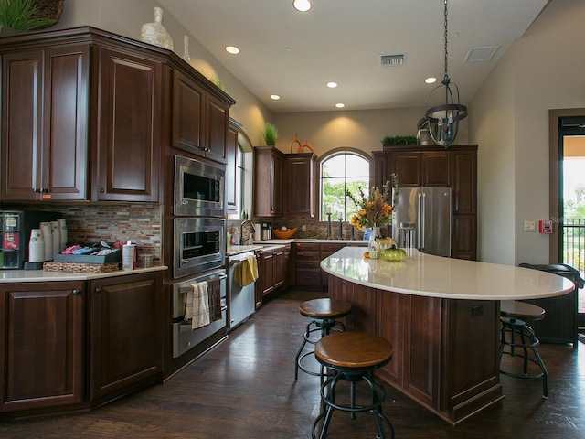 2525 Vaccaro Dr, Sarasota, FL 34231 - kitchen with visible vents, backsplash, a breakfast bar, and stainless steel appliances