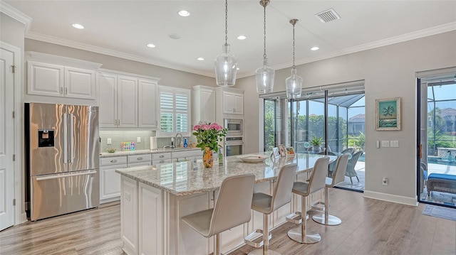 8713 Mangilli Rd, Sarasota, FL 34238 - kitchen with stainless steel appliances, white cabinets, light wood-style floors, recessed lighting, and crown molding