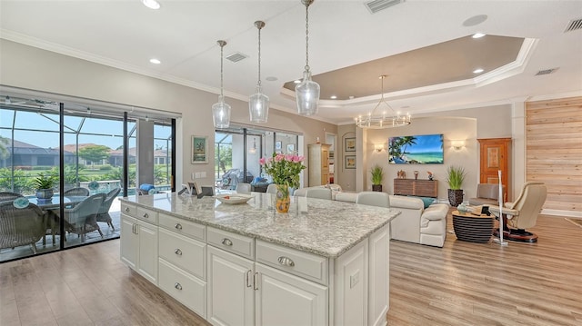 8713 Mangilli Rd, Sarasota, FL 34238 - kitchen featuring light wood-type flooring, white cabinets, ornamental molding, a kitchen island, and decorative light fixtures