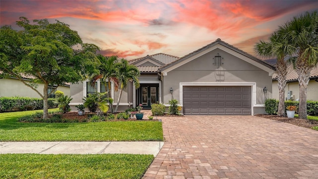 8713 Mangilli Rd, Sarasota, FL 34238 - view of front facade featuring stucco siding, decorative driveway, a front lawn, and a garage