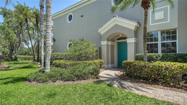 doorway to property featuring a yard and stucco siding