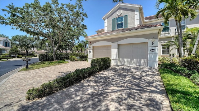 mediterranean / spanish-style house with an attached garage, stucco siding, driveway, and a tiled roof
