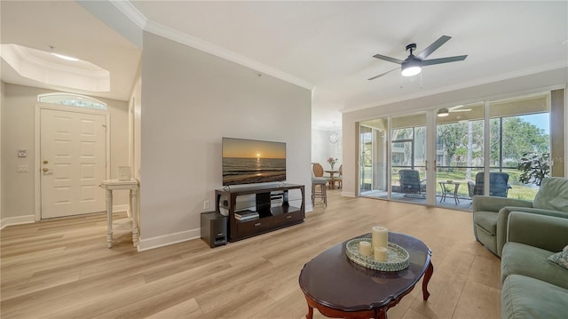 living area with crown molding, baseboards, light wood-style floors, and a ceiling fan