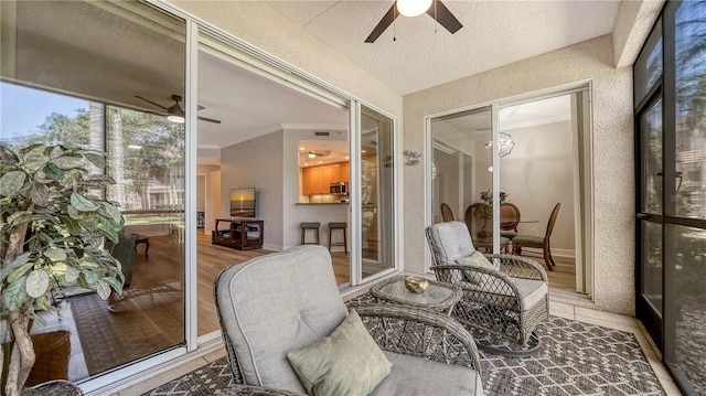 sunroom with visible vents, ornamental molding, and ceiling fan
