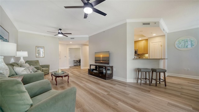 living room featuring baseboards, a ceiling fan, light wood-style flooring, and ornamental molding