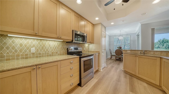 kitchen with light wood-style floors, appliances with stainless steel finishes, a sink, and light brown cabinets