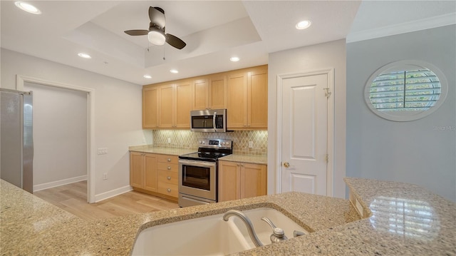 kitchen featuring light brown cabinets, decorative backsplash, stainless steel appliances, and light wood-style flooring