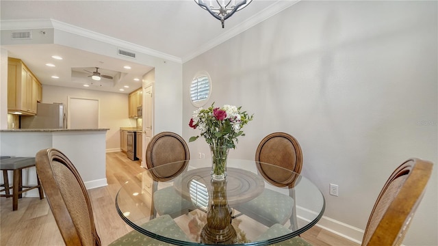dining room with baseboards, ornamental molding, light wood-type flooring, and visible vents