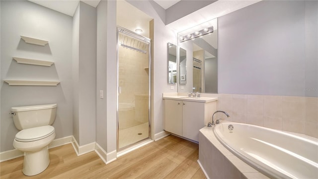 bathroom with a shower stall, wood finished floors, a bath, and vanity