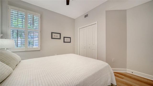 bedroom featuring light wood-style floors, baseboards, multiple windows, and a closet